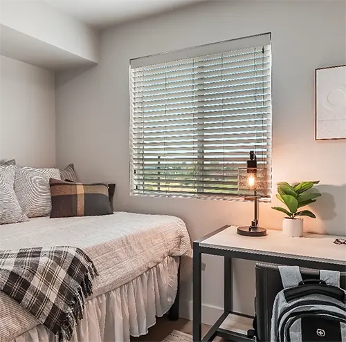 View of desk, bed, and TV in private student bedroom at UC